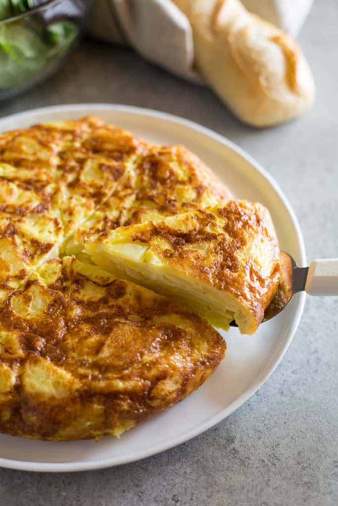 Tortilla de papa on a plate with a slice being served